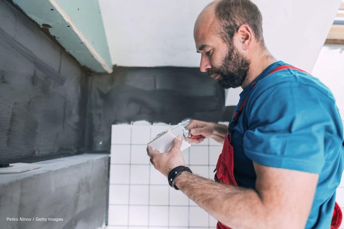 Handwerker verlegt Fliesen in einer Wandnische in einem neuen Badezimmer