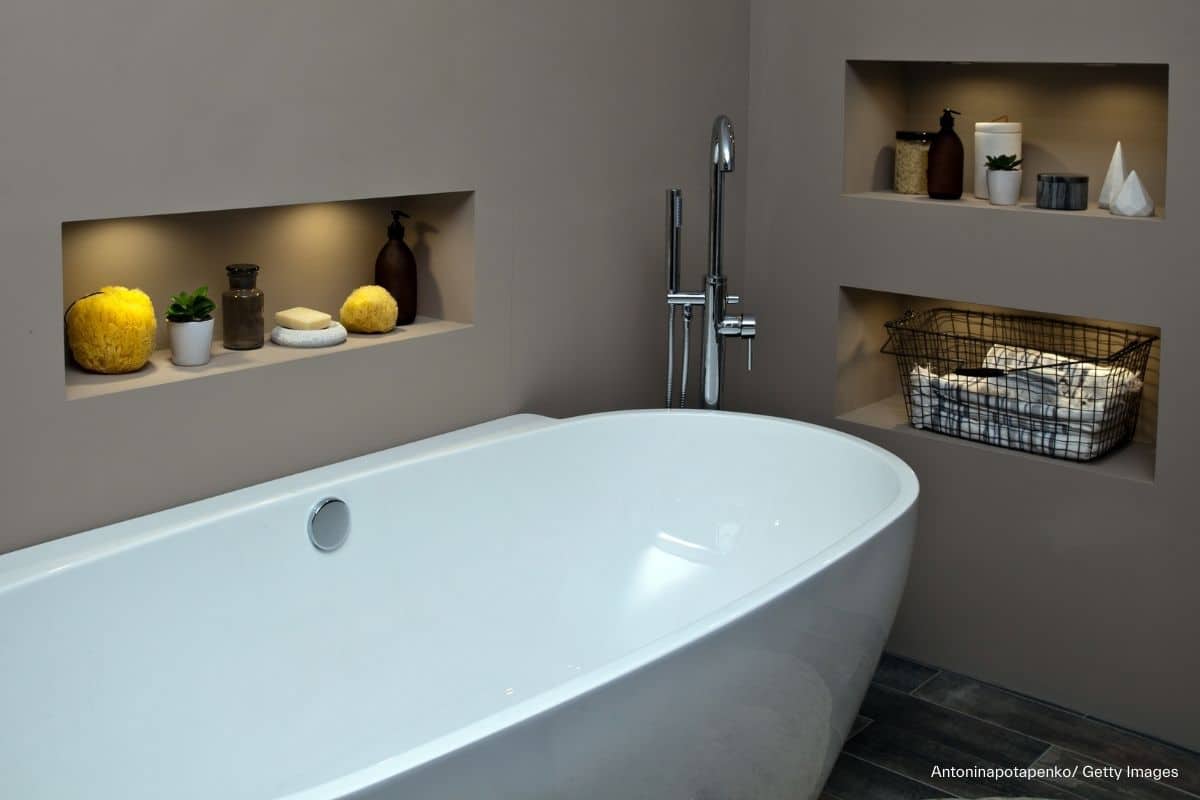 Badezimmerecke mit einer freistehenden, runden Badewanne und drei beleuchteten Wandnischen mit Badzubehör in den anliegenden Wänden