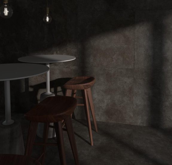 Café Interieur mit Tischen und Hockern, bei dem Boden und Wand mit den Living Ceramics Betonoptik-Fliesen Floss ausgestattet sind