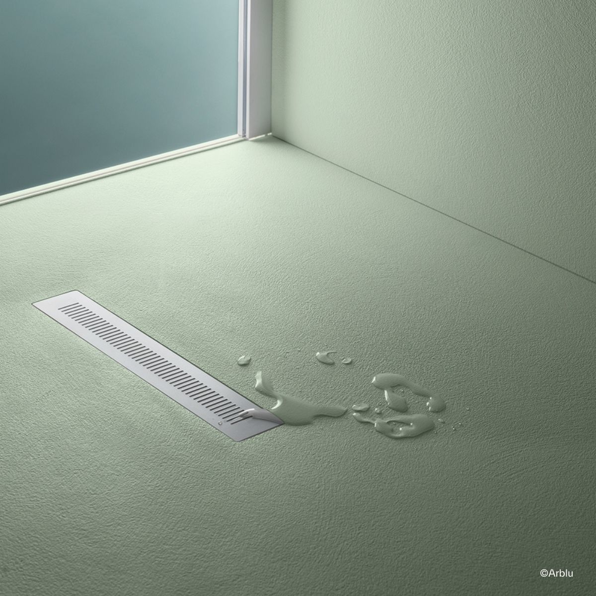 Close-up des Bodens einer Arblu Easystone Dusche mit einem Spalt-Abfluss und einer kleinen Wasserpfütze daneben