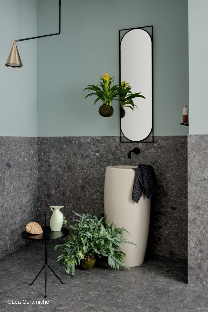 augenscheinlich fugenlose Waschtisch-Ecke mit halbhoch gefliester Wand und gefliestem Boden, gestaltet mit Natursteinoptik-Fliesen der Serie Side Stone von Lea Ceramiche, im oberen Bereich der Wand blassblau gestrichen