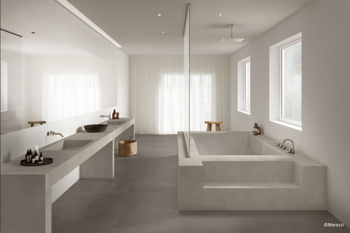 Badezimmer mit Duschwanne und doppeltem Waschtisch, auf dem Boden graue Betonoptik-Fliesen aus der Serie Grande Concrete Look von Marazzi