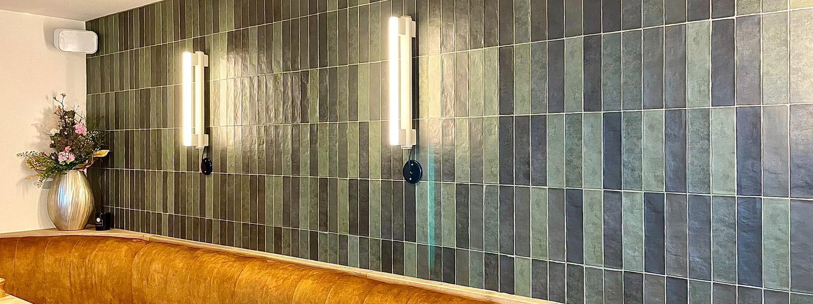 Wand in &uuml;ber einer Restauraunt-Sitzecke, verkleidet mit REVOIR PARIS Fliesen der Serie Atelier Emeraude Mat