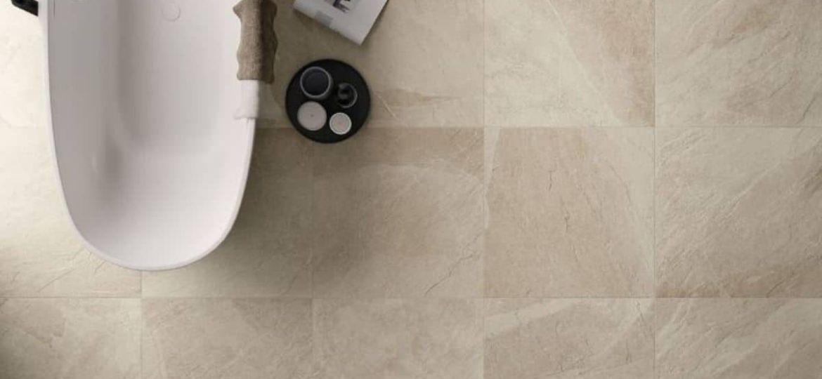 Beiges Badezimmer mit den Fliesen Shale in der Farbe Sand von Italgraniti auf dem Boden verlegt sowie eine freistehende weiße Badewanne