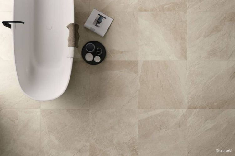 Beiges Badezimmer mit den Fliesen Shale in der Farbe Sand von Italgraniti auf dem Boden verlegt sowie eine freistehende wei&szlig;e Badewanne