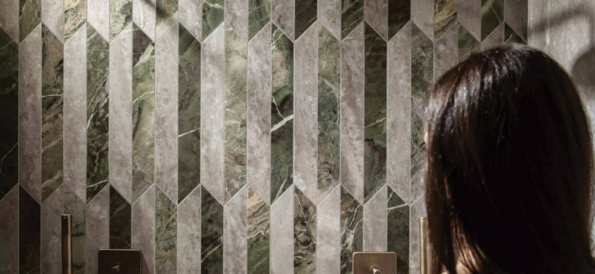 Frau schaut auf Dusche gestaltet mit Fliesen der Serie Heritage Luxe (Picket Mix), Marmoroptik in kleinen Formaten zweifarbig verlegt