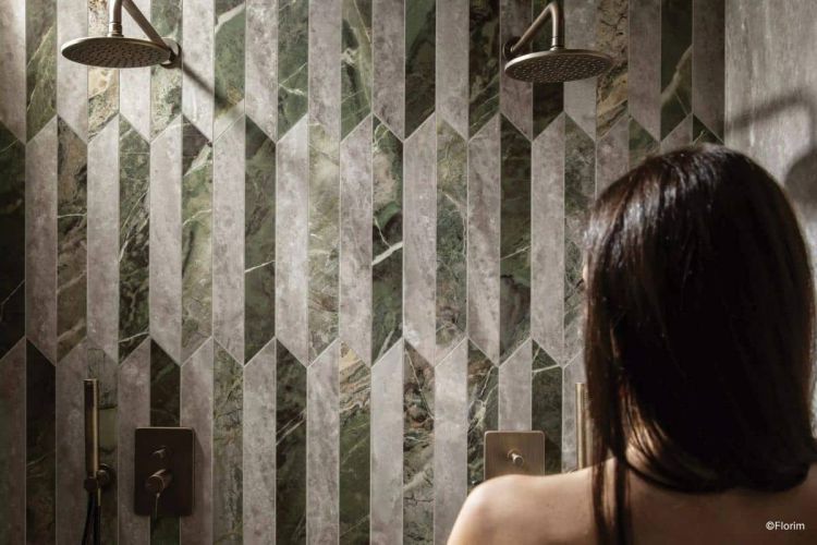 Frau schaut auf Dusche gestaltet mit Fliesen der Serie Heritage Luxe (Picket Mix), Marmoroptik in kleinen Formaten zweifarbig verlegt