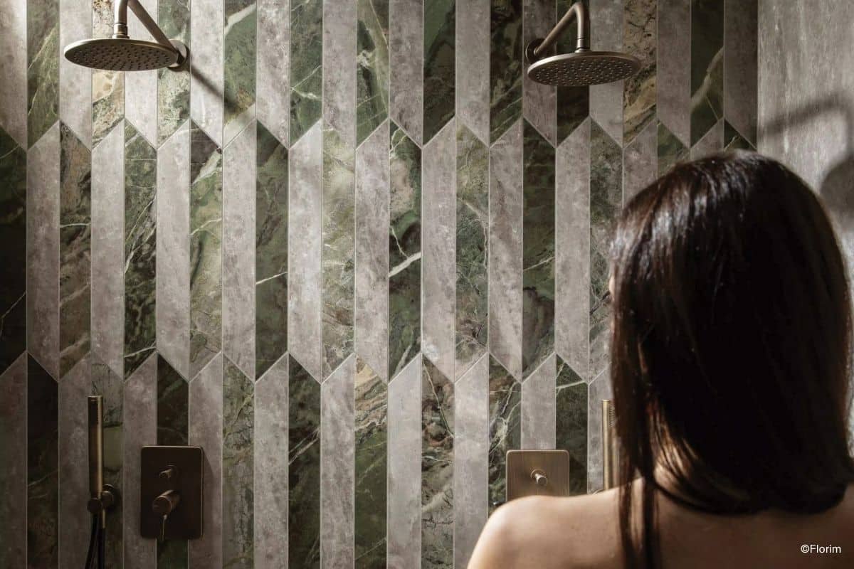 florim-heritage-luxe-picket-mix-duschfliesen Frau schaut auf Dusche gestaltet mit Fliesen der Serie Heritage Luxe (Picket Mix), Marmoroptik in kleinen Formaten zweifarbig verlegt